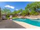 Lounge seating by a sparkling pool with a rock waterfall and lush landscaping create a backyard retreat at 10558 E Meadowhill Dr, Scottsdale, AZ 85255