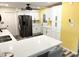 Bright kitchen with stainless steel refrigerator, white cabinets, and a yellow accent wall at 1132 S 81St Pl, Mesa, AZ 85208