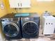 Modern laundry room featuring a washer and dryer with white storage and yellow walls at 1132 S 81St Pl, Mesa, AZ 85208