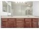 Bathroom featuring double sinks, wood cabinets, a shower, and a large mirror at 12603 W Blackstone Ln, Peoria, AZ 85383