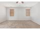 This primary bedroom features neutral colored walls, a ceiling fan, and two large windows with wooden blinds at 12603 W Blackstone Ln, Peoria, AZ 85383