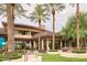 A view of the clubhouse exterior with elegant outdoor seating beneath mature palm trees at 13055 W Cliffrose Rd, Peoria, AZ 85383