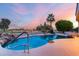 Swimming pool with a rock waterfall feature and lush desert landscaping, framed by palm trees at 19793 N Tapestry Ct, Surprise, AZ 85374