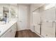 Bathroom featuring wood-look floors, double sinks, a glass-enclosed shower, and white cabinets at 22854 E Pummelos Rd, Queen Creek, AZ 85142