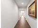 Inviting hallway with wood-look flooring and neutral walls, enhanced by a decorative framed painting at 22854 E Pummelos Rd, Queen Creek, AZ 85142