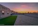 View of the house and backyard with gravel, artificial turf, block wall at sunset at 30116 W Fairmount Ave, Buckeye, AZ 85396