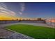 Backyard with gravel ground cover, block wall, and artificial turf section at sunset at 30116 W Fairmount Ave, Buckeye, AZ 85396