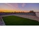 Wide shot of backyard with artificial turf, gravel ground cover, and block wall at sunset at 30116 W Fairmount Ave, Buckeye, AZ 85396