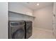 This laundry room features a washer and dryer, tile floors and white shelves at 30116 W Fairmount Ave, Buckeye, AZ 85396