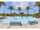 Community splash pad with vibrant play structures and ample seating surrounded by towering palm trees in the sunshine at 30116 W Fairmount Ave, Buckeye, AZ 85396