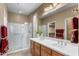 Well-lit bathroom with a double sink vanity, glass-enclosed shower, and modern fixtures at 4542 E Carob Dr, Gilbert, AZ 85298