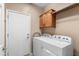 Functional laundry room with modern appliances, overhead cabinet, and a door to the home's exterior at 4542 E Carob Dr, Gilbert, AZ 85298