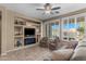 Bright living room featuring a ceiling fan, built-in shelves, modern fireplace, and plantation shutters at 4542 E Carob Dr, Gilbert, AZ 85298