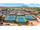 Overhead shot of the tennis courts with lush landscaping and community buildings with parking and mountain views at 4542 E Carob Dr, Gilbert, AZ 85298