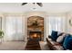 Cozy living room with fireplace, stone facade, soft curtains and large couches with a chest coffee table at 5471 W Quail Ave, Glendale, AZ 85308