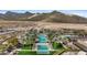 Aerial view of community pools featuring multiple pools, palm trees, manicured lawns, and stunning mountains at 5644 N 206Th Gln, Buckeye, AZ 85396