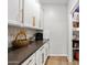 Featuring a pantry with white cabinets, backsplash and countertops with a doorway that goes into a storage area filled with supplies at 5644 N 206Th Gln, Buckeye, AZ 85396