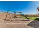 A playground with swings and a slide sit on a sand base and artificial grass in this backyard at 7531 W Rock Springs Dr, Peoria, AZ 85383