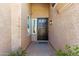 Front door entrance with a black multi-paneled door, stucco walls, and green shrubbery at 7919 E Posada Ave, Mesa, AZ 85212