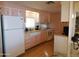 Cozy kitchen featuring pink and white cabinetry, a white refrigerator, and laminate wood flooring at 8600 E Broadway Rd # 22, Mesa, AZ 85208