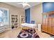 Bright home office boasts blue accent wall, white shelving, desk, and decorative rug at 9336 W Louise Dr, Peoria, AZ 85383