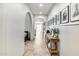 Hallway featuring tiled floors, arched doorways, and stylish decor including framed photos and console table at 9742 W Los Gatos Dr, Peoria, AZ 85383