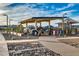 Community playground featuring modern equipment, shaded seating, and a paved walkway under blue sky at 9742 W Los Gatos Dr, Peoria, AZ 85383