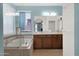 Bathroom featuring double sinks, a soaking tub with glass enclosure, a large window, and blue accent wall at 11305 W Monte Vista Rd, Avondale, AZ 85392