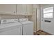 Functional laundry room with ample storage cabinets and tile floors at 13808 N Silverbell Dr, Sun City, AZ 85351