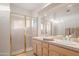 Bathroom featuring a glass shower enclosure, dual sinks, and neutral color palette at 15145 W Catalina Dr, Goodyear, AZ 85395