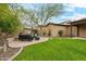 Well-manicured backyard with a built-in stone fireplace, seating area, and lush lawn perfect for entertaining at 17727 N 95Th Pl, Scottsdale, AZ 85255