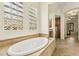 Bright bathroom featuring tiled tub and a glass block window, providing natural light at 17727 N 95Th Pl, Scottsdale, AZ 85255