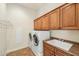 Functional laundry room features a washer, dryer, utility sink, and upper cabinets at 17727 N 95Th Pl, Scottsdale, AZ 85255