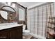 Bathroom showcasing floral wallpaper, round mirror, floating shelf and a shower with a striped curtain at 18835 N Mayan Dr, Sun City, AZ 85373