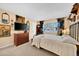 Cozy bedroom featuring neutral walls, carpet, a window with plantation shutters and a black iron bed frame at 18835 N Mayan Dr, Sun City, AZ 85373