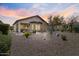 Backyard with desert landscaping, covered patio, and outdoor seating areas under a vibrant sunset sky at 21232 N 262Nd Dr, Buckeye, AZ 85396