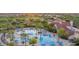 Aerial view of a large community pool area with palm trees, umbrellas, lounge chairs and views of nearby rooftops at 21232 N 262Nd Dr, Buckeye, AZ 85396