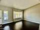 Empty living room featuring dark wood floors and two large windows at 24809 N 41 Ave, Glendale, AZ 85310