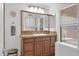 Cozy bathroom featuring tiled countertops, wood cabinetry and a decorative mirror and wall clock at 4718 E Mossman Rd, Phoenix, AZ 85050