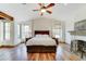 Main bedroom featuring a king bed, fireplace, wood floors, ceiling fan, and three windows at 6915 E Gary Rd, Scottsdale, AZ 85254