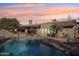 Relaxing poolside view of the home with an outdoor kitchen area, seating under a pergola, and desert landscaping at 6915 E Gary Rd, Scottsdale, AZ 85254