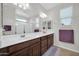 Bathroom featuring a dual sink vanity with dark wood cabinetry, a large mirror, and a walk-in shower at 7576 W Fetlock Trl, Peoria, AZ 85383