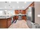 Well-lit kitchen featuring dark granite countertops, stainless steel appliances, cherry-wood cabinetry, and island seating at 7576 W Fetlock Trl, Peoria, AZ 85383