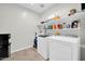 Functional laundry room equipped with modern washer and dryer, shelving for storage, and tiled flooring at 7576 W Fetlock Trl, Peoria, AZ 85383