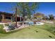 Expansive backyard featuring a pool, putting green, mature landscaping, and outdoor lighting for evening enjoyment at 8233 E Foothill Cir, Scottsdale, AZ 85255