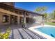 Back patio with travertine tile, outdoor fireplace, and cooling mist system overlooking a lush lawn and pool at 8233 E Foothill Cir, Scottsdale, AZ 85255