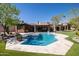 Inviting backyard pool featuring travertine tile, lush landscaping, and an outdoor kitchen for luxurious outdoor living at 8233 E Foothill Cir, Scottsdale, AZ 85255