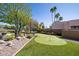 Beautiful backyard putting green with lush landscaping, mature trees, and a charming desert aesthetic at 8233 E Foothill Cir, Scottsdale, AZ 85255