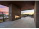 Inviting covered patio featuring a modern fireplace, desert landscaping, and views of the sunset at 10354 E Celestial Dr, Scottsdale, AZ 85262