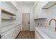 Modern laundry room with white cabinets, stone countertops, and wood laminate flooring at 11267 E Beck Ln, Scottsdale, AZ 85255